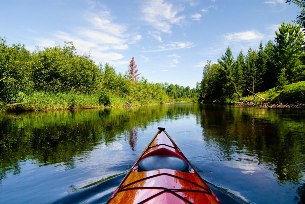 photo of people riding kayaks on river through fields